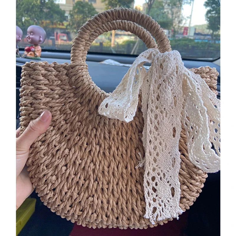 Borsa paglia intrecciata semicircolare in paglia naturale, beige e khaki, con manici rotondi e versione con fiocco Ribbon, vista frontale su fondo neutro