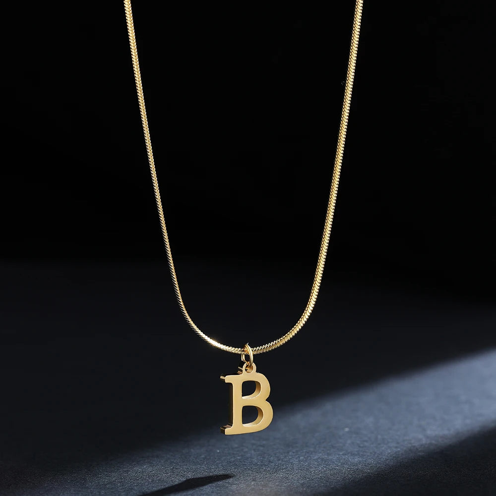 Collana iniziale A–Z in acciaio placcato oro con snake chain – pendente minimal su collare clavicolare
