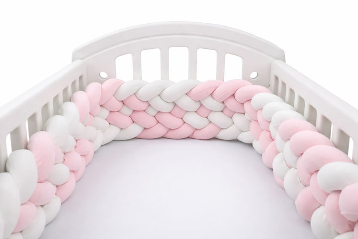 Paracolpi culla intrecciato rosa e bianco morbido per lettino neonato su sfondo bianco