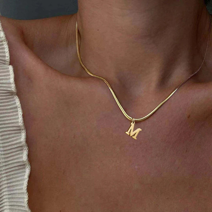 Collana iniziale A–Z in acciaio placcato oro con snake chain – pendente minimal su collare clavicolare