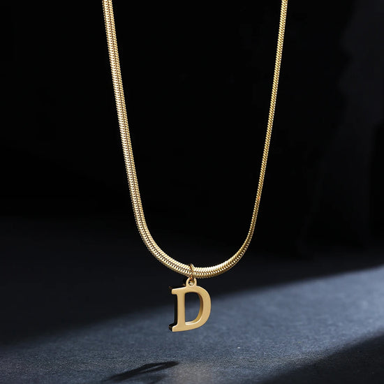 Collana iniziale A–Z in acciaio placcato oro con snake chain – pendente minimal su collare clavicolare