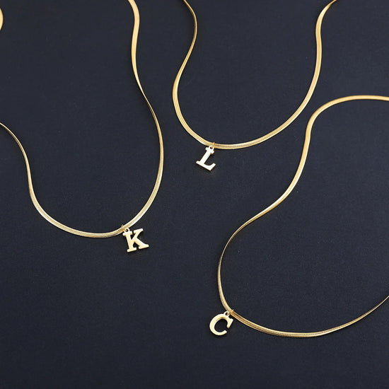 Collana iniziale A–Z in acciaio placcato oro con snake chain – pendente minimal su collare clavicolare